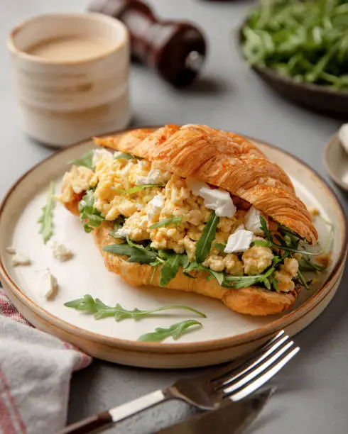 Croissant sandwich scrambled eggs. Closeup view. Tasty healthy breakfast sandwich
