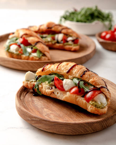 istock Croissant with mozzarella, tomato and arugula on wooden board. 1387158612