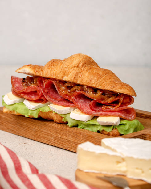 istock Close up sandwich with salami, brie cheese, caramelized onion and salad. 1387158621