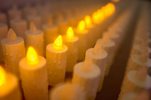 support de lampe électronique avec quelques bougies allumées dans une église - bougie led photos et images de collection