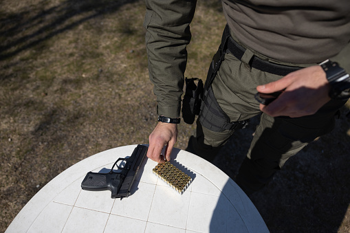 Man putting bullets into the bullet cartridge at the shooting range outdoors.