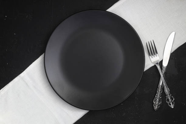istock Empty black slate plate on dark stone table. Food background for menu, recipe. Table setting. Flatlay, top view. Mockup for restaurant dish 1387168236