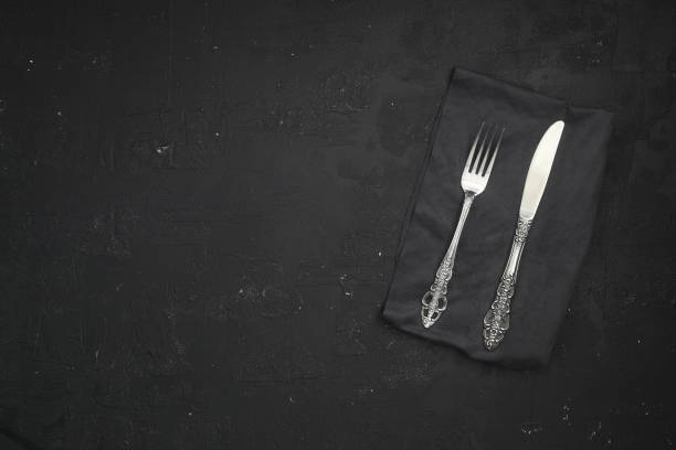 istock Overhead shot of silverware on black table with copy space. 1387168320