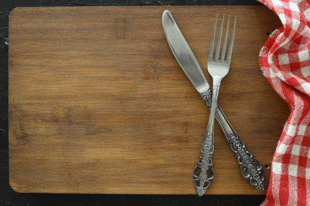 istock Blackboard or black cutting board and cutlery, food background with copy space for text. Web banner, design, menu concept 1387168402
