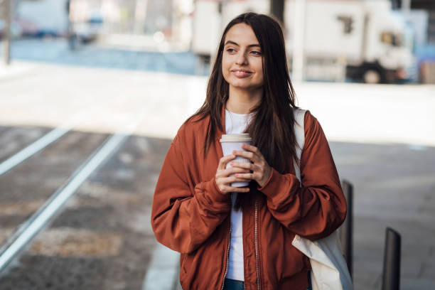 istock Girl standing on street with coffee 1387172244