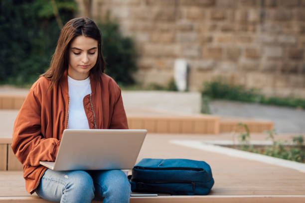 istock Girl using her laptop outside 1387172272