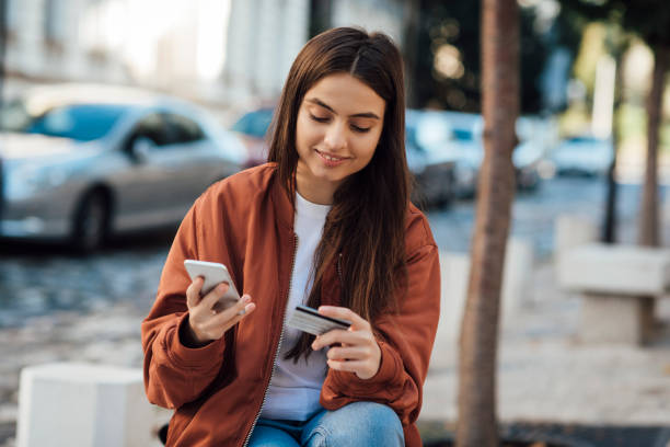 istock Happy girl using phone and credit card 1387172274