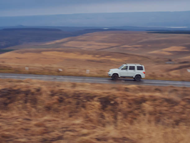 istock SUV rides on the road surrounded by autumn fields and hills. Blurred image. North Caucasus landscape.Blurred image 1387174910