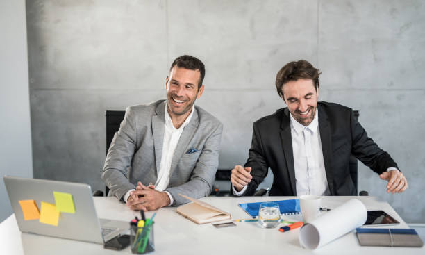 Happy businessmen having fun in office. Two cheerful young businessmen taking a break from work and laughing. office buddies stock pictures, royalty-free photos & images