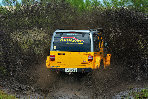 Cidreira, Rio Grande do Sul, Brazil - Apr 02nd, 2016: Yellow off-road sport truck splashing on a muddy puddle road