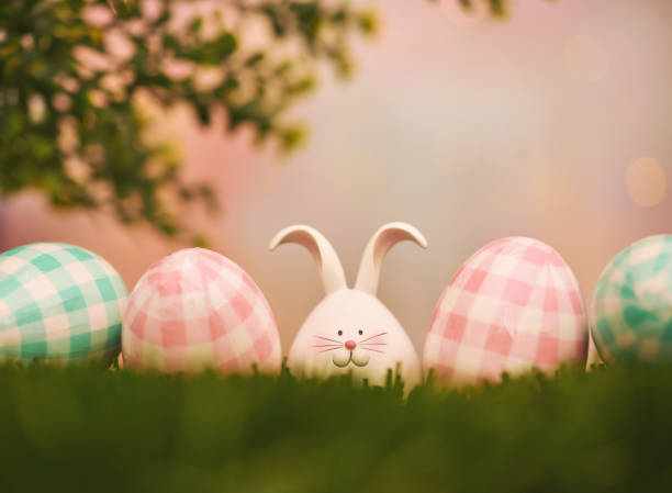istock Easter background with pink and blue plaid eggs and a cute Easter bunny. Space for copy 1387187420