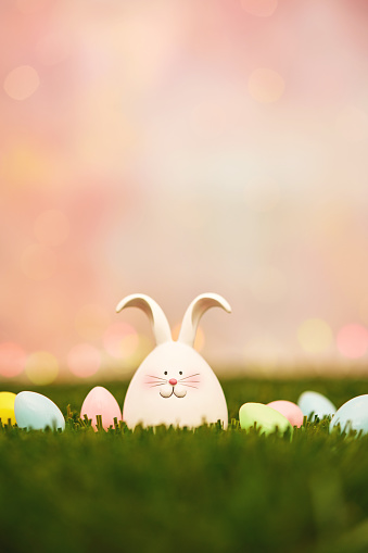 Easter background with cute Easter bunny in grass with tiny Easter eggs and copy space