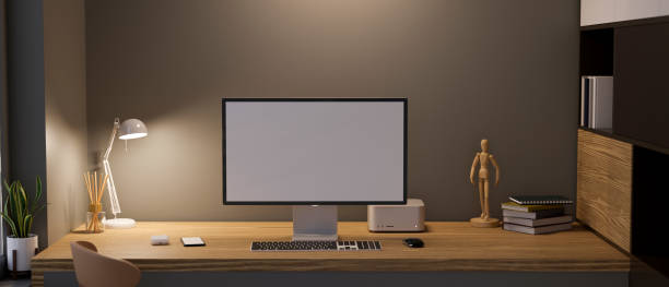 istock Modern stylish office studio workspace with computer on wooden table against dark wall. 1387187762