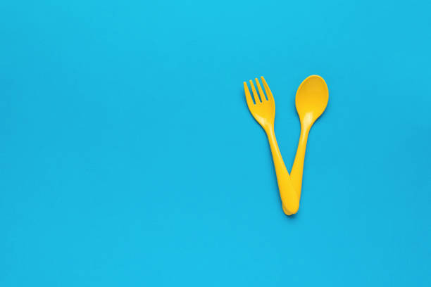 istock Yellow children's plastic fork and spoon on a blue background. A place for your text. Flat lay. 1387188564