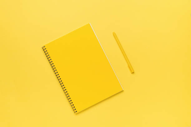 istock A bright yellow notebook with a yellow pen on a yellow background. Flat lay. 1387188572