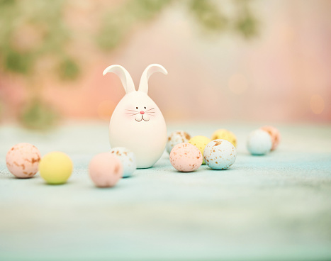 Dreamy Easter background with a cute Easter bunny and speckled Easter candy. Space for copy