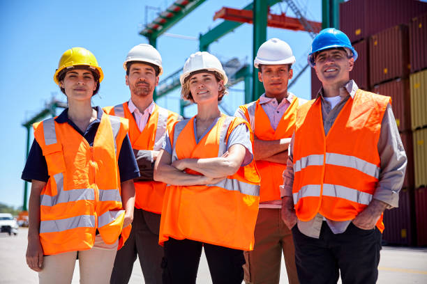 istock Group of engineers and cargo handlers wearing protective helmet standing at container terminal 1387191930