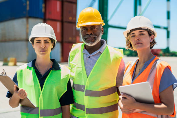 istock Foreman engineer and dock workers standing at shipping yard looking at the camera 1387191995