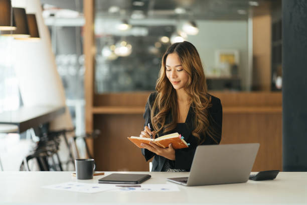 istock Business asian woman taking note on note book, Attractive girl working with laptop computer 1387191999
