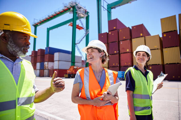 istock Dock control workers wearing hardhats and reflective vest walking on shipping container yard 1387192006