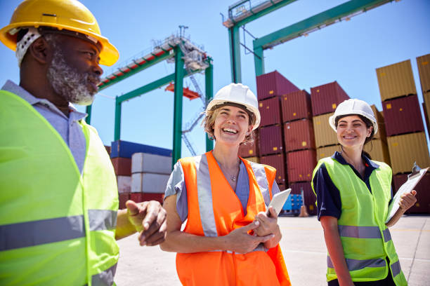 istock Dock control workers wearing hardhats and reflective vest walking on shipping container yard 1387192007