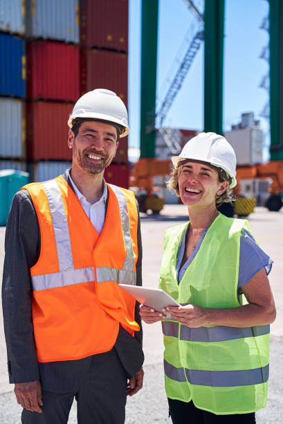 istock Cheerful dock control coworkers standing at shipping yard while holding digital tablet 1387192035