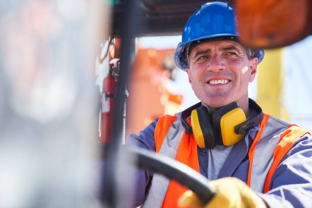 istock Male dock worker driving forklift at shipping yard 1387192687