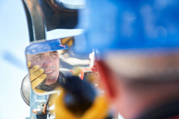 reflexion auf dem rückspiegel eines männlichen hafenarbeiters, der sich auf walkie-talkie unterhält - harbor commercial dock engineer service stock-fotos und bilder