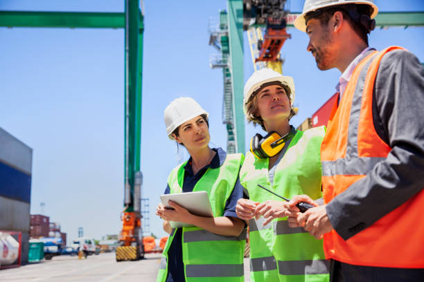 Dock control coworkers discussing cargo management over digital tablet Low angle view of dock control coworkers discussing cargo management over digital tablet during meeting at shipping container yard traceability stock pictures, royalty-free photos & images