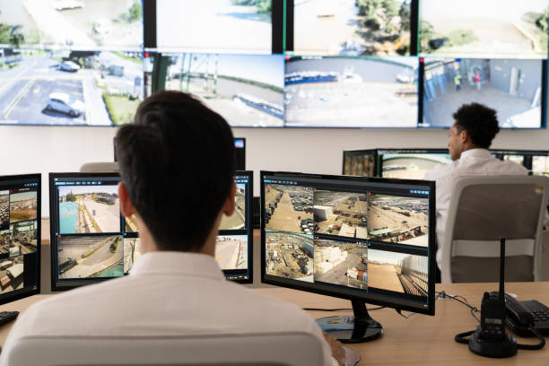 Security guards working at control room while looking at video wall stock photo