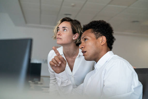 Female and male security coworkers discussing while looking and pointing up stock photo