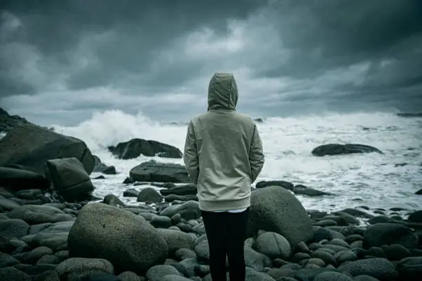 Photo of A woman looking at the waves of the sea alone in storm day