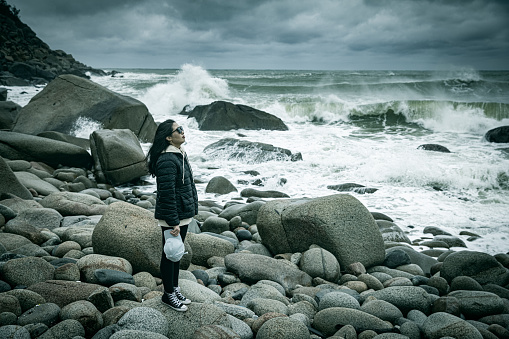 A woman looking at the waves of the sea alone in storm day