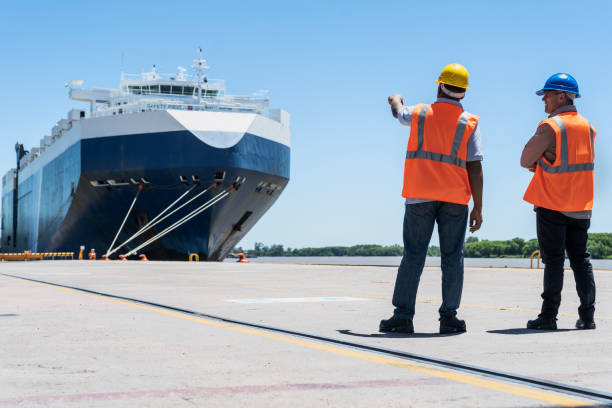 istock Dock control coworkers pointing and with arms crossed discussing work at shipping yard 1387193369