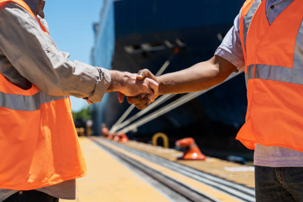 istock Male foreman engineer and dock worker shaking hands after meeting 1387193417