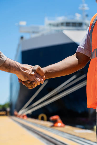 istock Male foreman engineer and dock worker shaking hands after meeting 1387193419