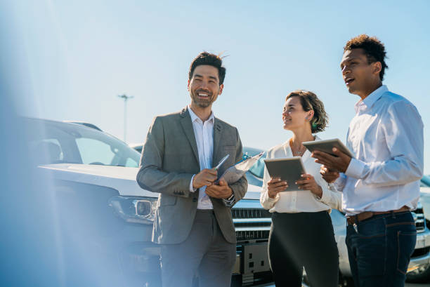Car salesmen and saleswoman discussing over digital tablet while laughing stock photo