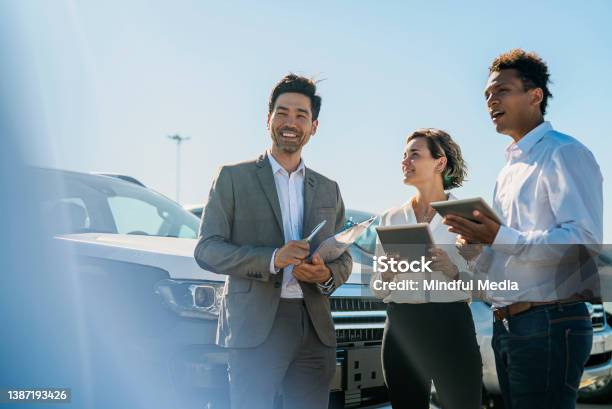 Car Salesmen And Saleswoman Discussing Over Digital Tablet While Laughing Stock Photo - Download Image Now