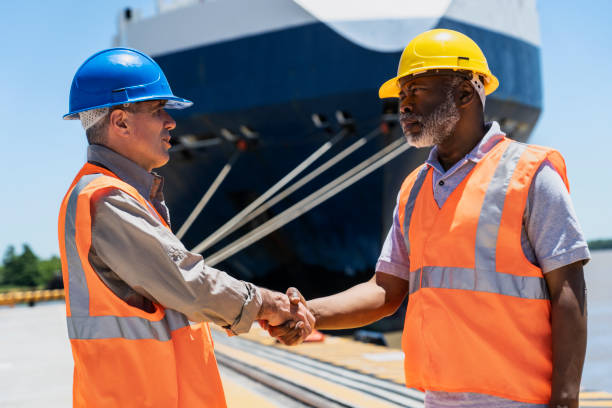 istock Male foreman engineer and dock worker shaking hands after discussing project 1387193437