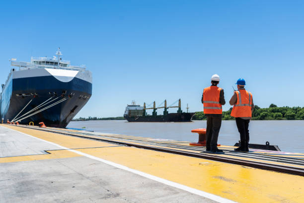 Male cargo handler and customs broker looking at cargo ship on river stock photo