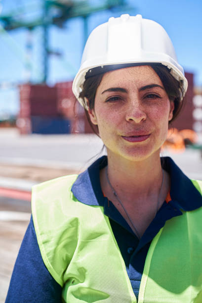 istock Female dock worker wearing hardhat looking at the camera 1387194103