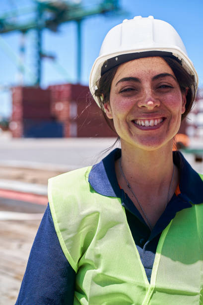 istock Female dock worker wearing hardhat looking and smiling at the camera 1387194148