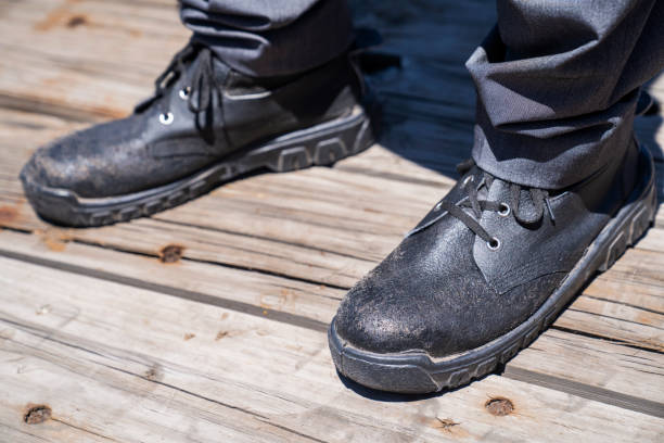 Low section of man wearing work boots standing on wooden deck