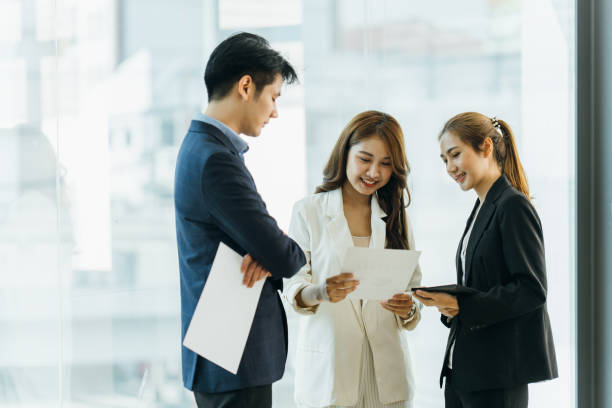 istock Young Asian woman leading business creative team in mobile application software design project. Brainstorm meeting, work together, internet technology, girl power, office coworker teamwork concept 1387200985