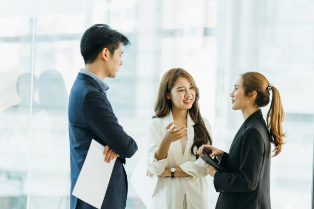 istock Young Asian woman leading business creative team in mobile application software design project. Brainstorm meeting, work together, internet technology, girl power, office coworker teamwork concept 1387201884