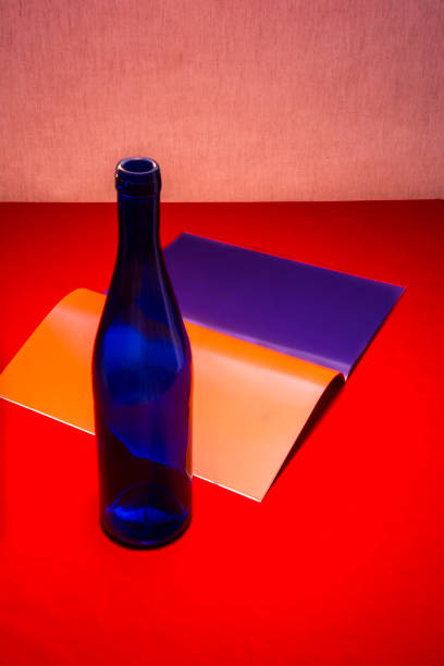 Still life with a blue bottle and notebook with colored sheets on a red table