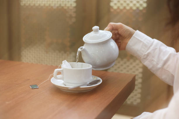 istock A woman pours tea into a mug for her morning breakfast 1387202704