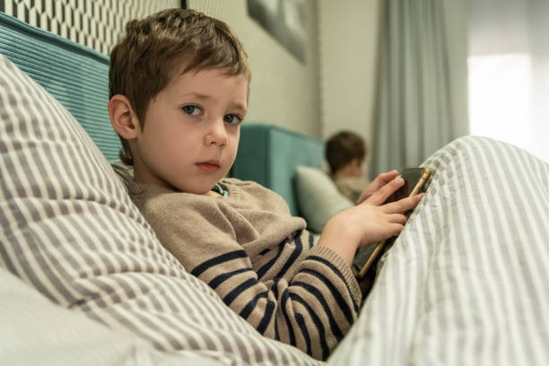 istock Little boy playing online game. Boy playing on a smart phone. 1387203792