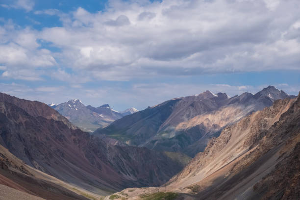 istock Beautiful mountain range with cloudy sky background. Hiking, trekking concept. Landscape background. Barskoon mountain pass. 1387208493