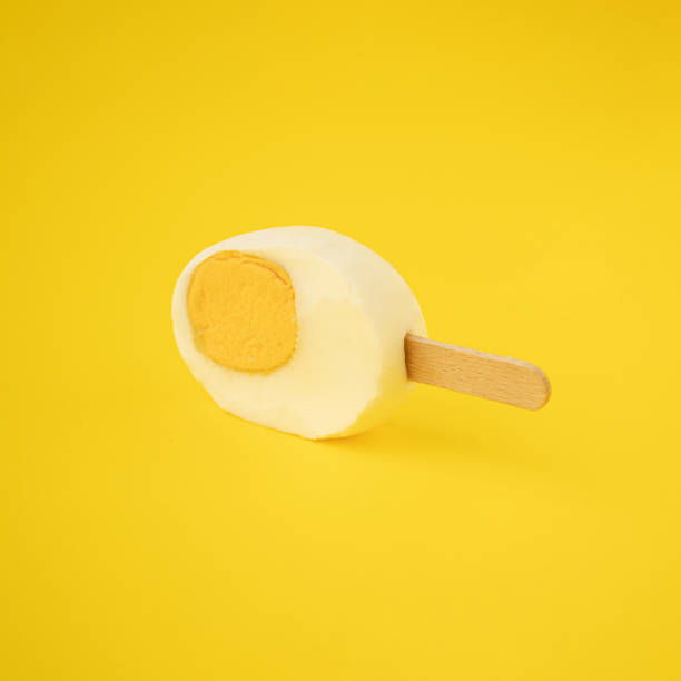 istock Freshly cut Easter egg with an ice cream stick against a yellow background 1387212674